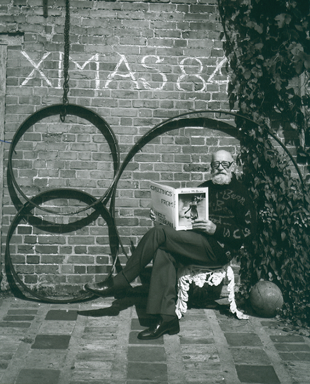 Angus McBean - Christmas Card 1984 - Self Portrait, Reading His Own Book in a Garden