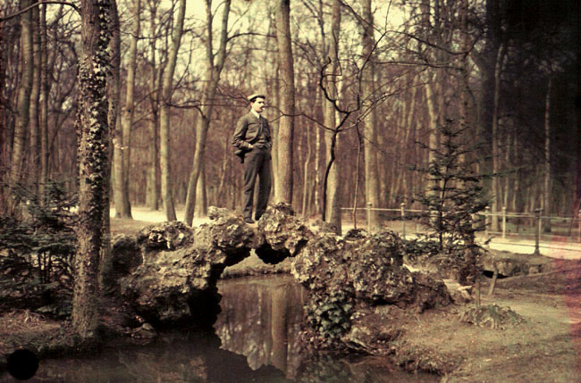 Anonymous - Man Standing on a Rocky Bridge over a Stream with Cigarette in His Mouth